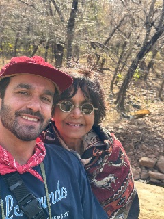 Raj stands with her son with a backdrop of woods