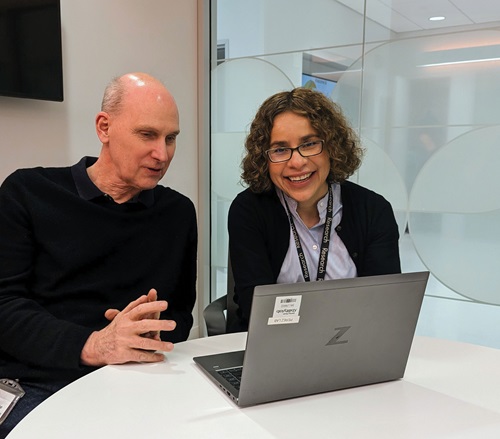 A man and women have a discussion while looking at a laptop