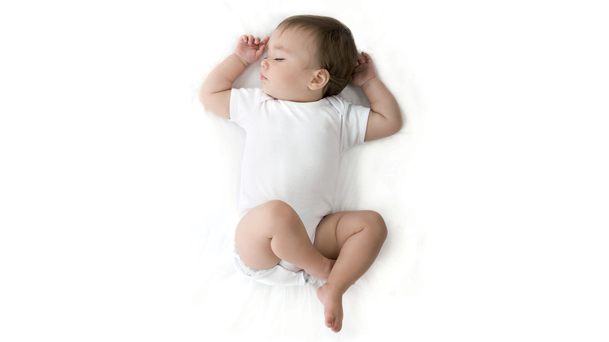 picture of an infant with brown hair wearing a white onesie
