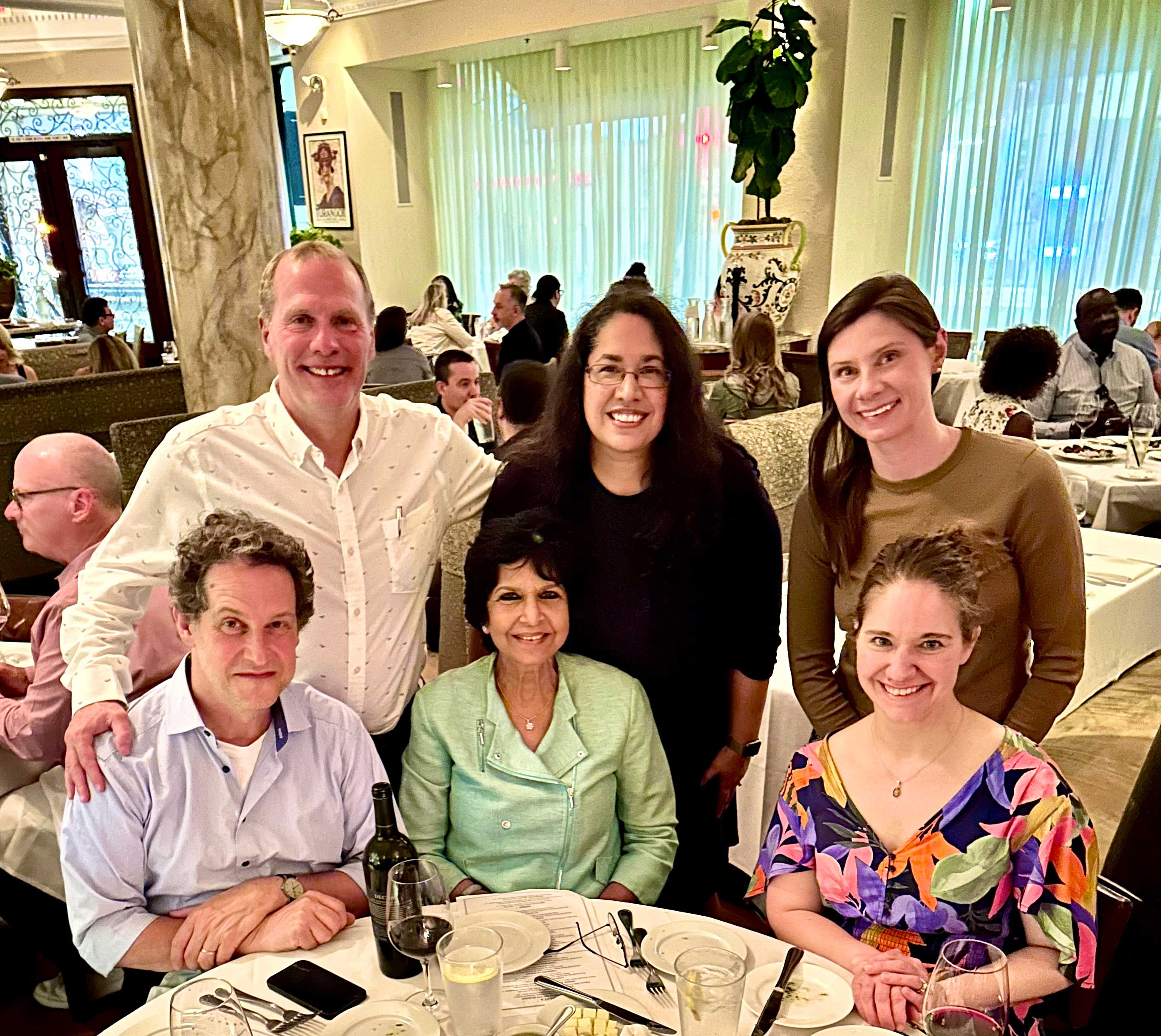 Feature_Art-and-Science_at-APS-Summit-2023 Six adults pose for a photo in a dining area. Raj is in the center