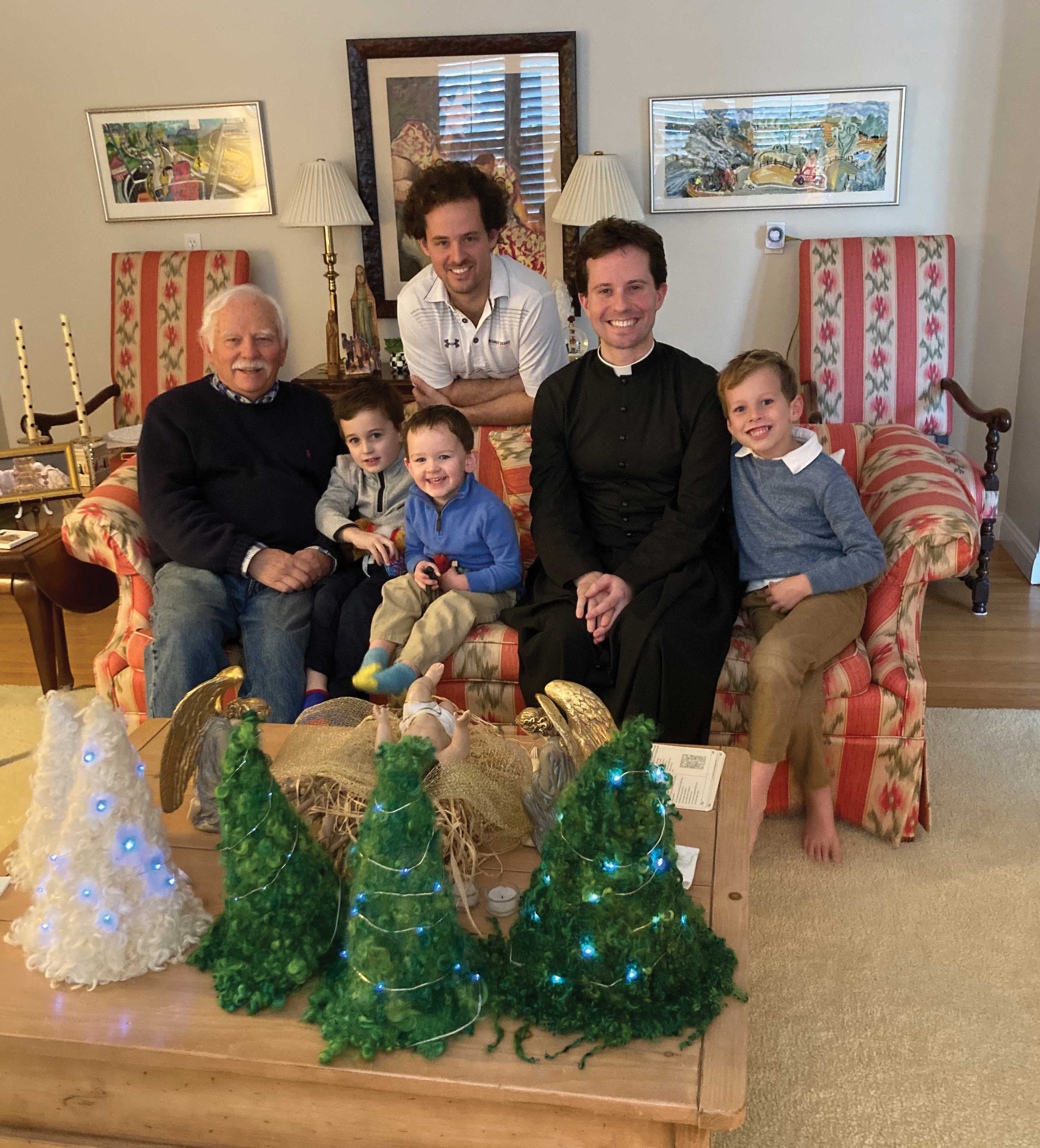 Feature_Samson_photo-4 Samson sits in a living room behind four small Christmas trees. Joining him are two adult twin men and three young children.